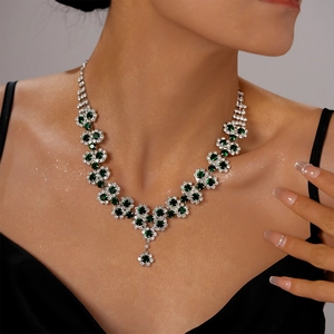 Close-up of luxury sun flower necklace featuring green gemstones and sparkling diamonds