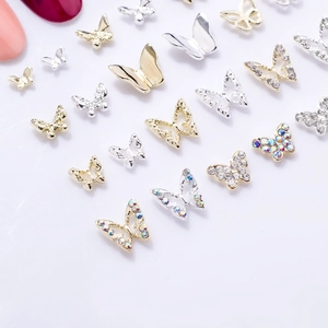 Detailed macro view of gold and silver mini metal butterfly nail charms with rhinestones
