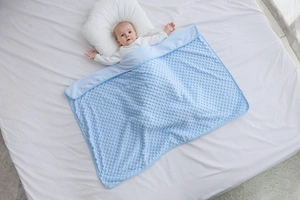 Dettaglio coperta azzurra per neonati con morbida texture a bolle 3D e rilievi tattili