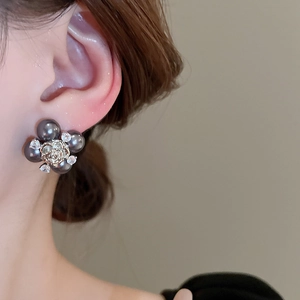 Détail de boucles d'oreilles fleur avec perles gris foncé, rose dorée et zircons