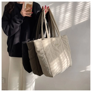 Detailed quilted nylon tote bags in black, dark brown and cream colors shown by a model