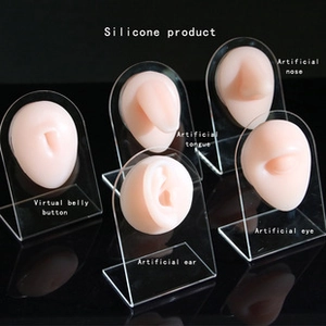 Modelli in silicone di parti del corpo per pratica piercing su supporto acrilico