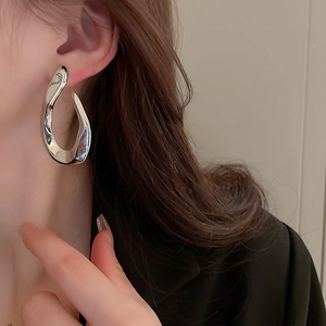 Macro detail of silver twisted liquid metal earrings featuring a high-gloss finish