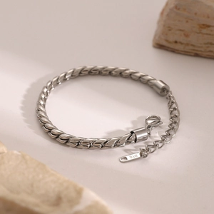 Detailed shot of silver stainless steel twisted rope chain with K18 tag on stone base