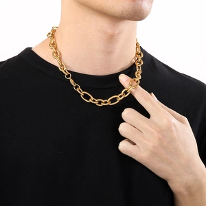 Close-up of a chunky golden stainless steel chain necklace worn on a black shirt
