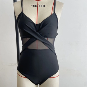 Detail of black one-piece swimsuit with crisscross straps and sheer mesh panels