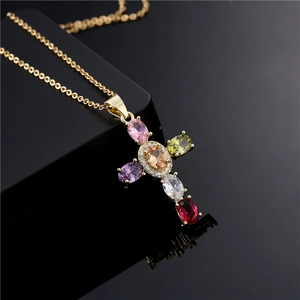 Elegant gold cross necklace with colorful oval zircons on reflective black background