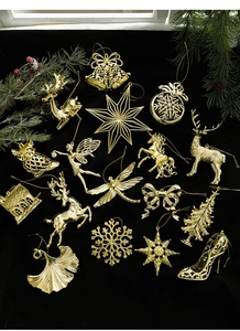 Close-up of assorted gold Christmas ornaments including reindeer and snowflakes on velvet