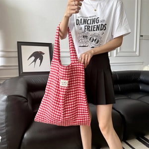 Close-up of red and white plaid knit tote bag with brand label in a modern living room