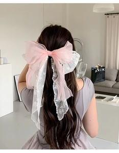 Detailed back view of pink mesh and white lace bow hair clip with long ribbons on model