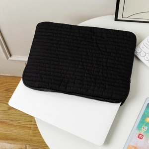 Detailed close-up of a black quilted laptop sleeve with horizontal padded protective lines
