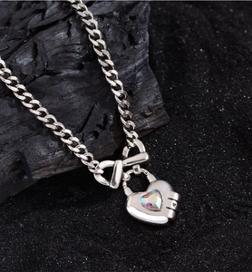 Close-up of silver chain with bow heart padlock pendant and colorful gemstone