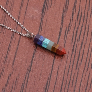 Minimalist hexagonal pendant necklace featuring colorful natural stone on a wood background