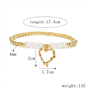 Detalle de pulsera de cuentas con perlas doradas y colgante de corazón rojo