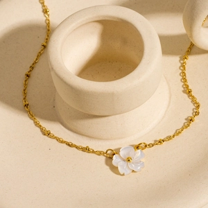 Macro view of a 18K gold-plated flower necklace featuring white mother-of-pearl carving