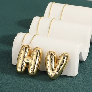 Detail of 18k gold bubble letter H and V pendants with inlaid cubic zirconia on box chains