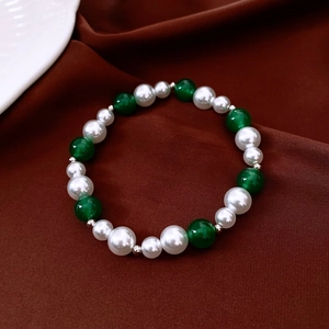 Detail view of pearl and green agate beaded bracelet on a premium brown silk background