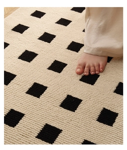 Close-up of woven geometric rug texture with a barefoot stepping on beige and black patterns