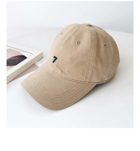 Close-up of beige cotton baseball cap with green embroidered number seven and twill texture