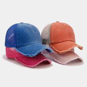 Dettaglio di cappellini trucker in rete invecchiata nei colori blu, arancio, rosa e fucsia
