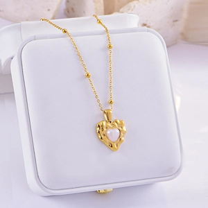 Golden heart necklace with pearl inlay and bead chain detail on white jewelry box