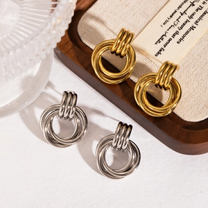 Golden and silver triple-hoop stainless steel earrings on an elegant wooden tray