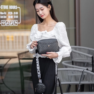 Detail of black V-quilted shoulder bag with stylish wide strap and mini round coin pouch