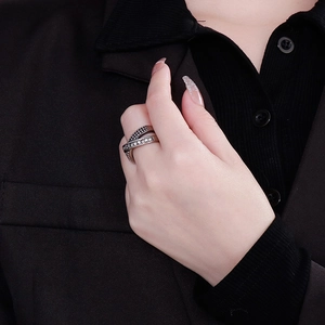 Crossed silver braided ring with black crystals on woman's index finger in vintage style