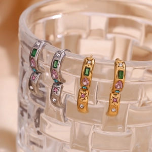 Détail de créoles en or 18 carats et argent avec zircons colorés suspendus sur un verre