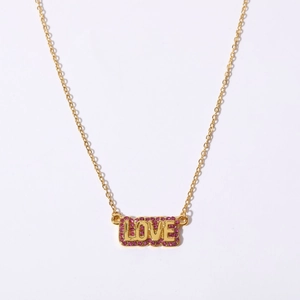 Close-up of golden rectangular necklace pendant with pink zircon LOVE lettering