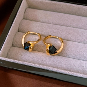 Close-up of gold-plated cubic hoop earrings with black geometric gemstones in a gift box