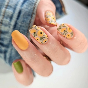 Short matte press-on nails featuring mustard green, yellow, and floral painted patterns