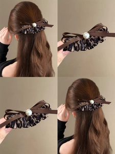 Close-up of leopard print bow hair clip with large pearl detail on brunette hair