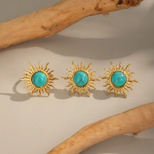 Detailed view of three vintage sun-shaped earrings with turquoise stones on wooden twigs