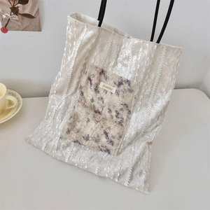 Detail of off-white canvas tote bag featuring vertical lace stripes and butterfly pocket