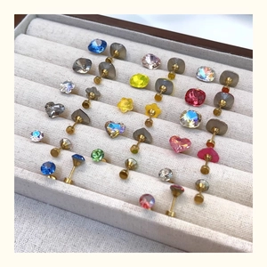 Macro shot of colorful crystal stud earrings in heart, star, and round shapes with gold pins