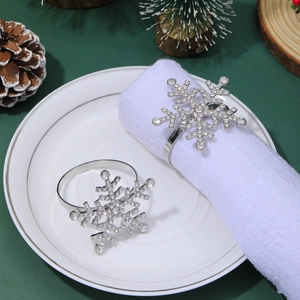 Detailed view of silver diamond-encrusted snowflake napkin rings on a white napkin
