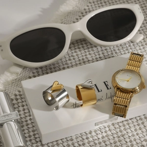 Close-up of golden quartz watch and two-tone heart rings on elegant white fabric