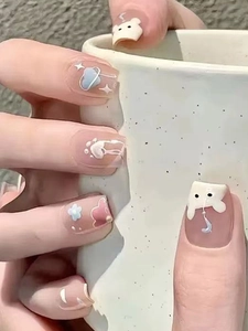Pink press-on nails with 3D cartoon bear and floral art held on a ceramic cup