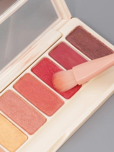 Macro detail of soft synthetic makeup brush picking up fine warm-toned eyeshadow powder
