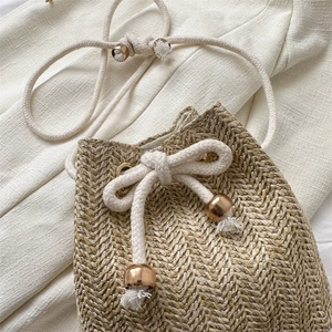 Handwoven straw bucket bag with drawstring closure and golden beads for summer beach look