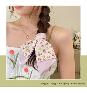 Close-up of pink floral bow hair scrunchie with layered fabric in a fresh summer style
