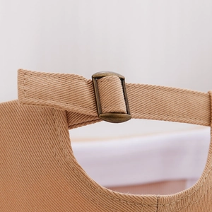 Detail of adjustable metal buckle and stitching on khaki cotton twill baby baseball cap