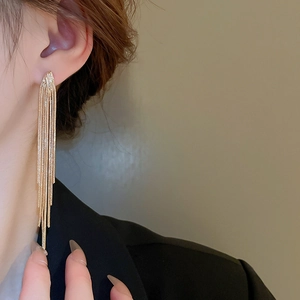 Close-up of elegant gold V-shaped chain tassel earrings worn by a female model