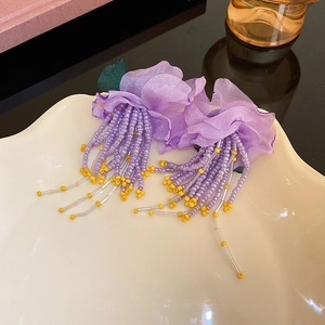Détail des boucles d'oreilles pétales en mousseline violette avec franges de perles