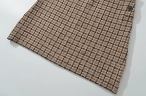Detailansicht von braun-schwarzem Hahnentritt-Tweed-Stoff mit Knopfverzierung