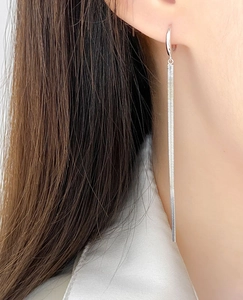 Close-up of silver long tassel earrings with snake chain pendant on a model