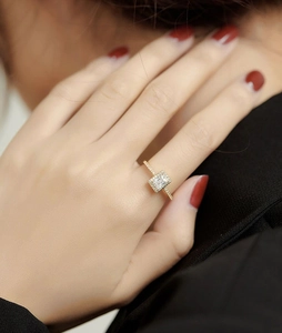 Close-up of a delicate gold square zircon ring worn by a model for a minimalist look
