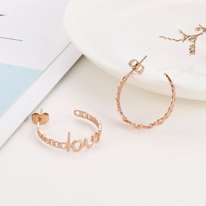 Detail shot of rose gold C-shaped earrings with love lettering and hollow chain texture