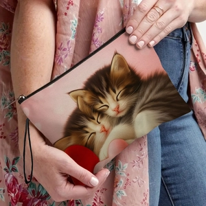 Trousse à maquillage en toile avec motif chats et dragonne tenue par un modèle